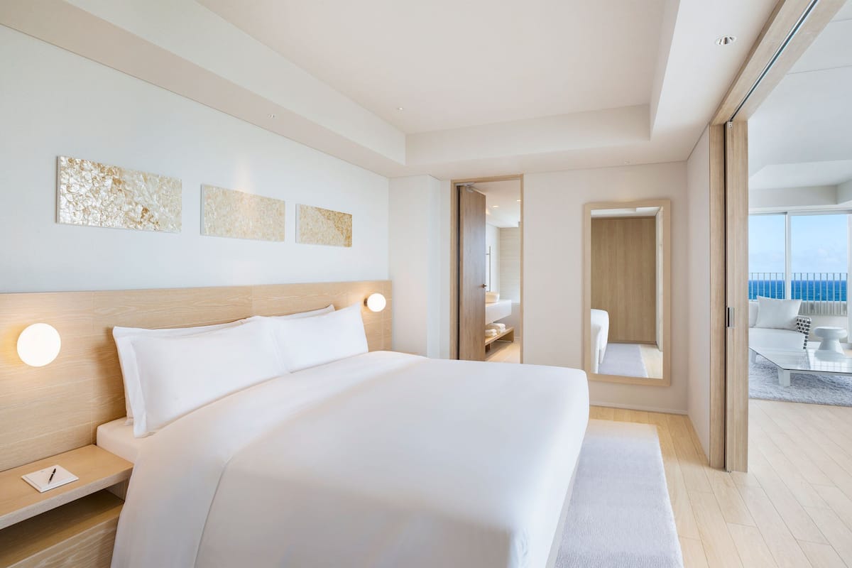 A modern hotel room with a large bed, bedside tables, and artwork on the wall.