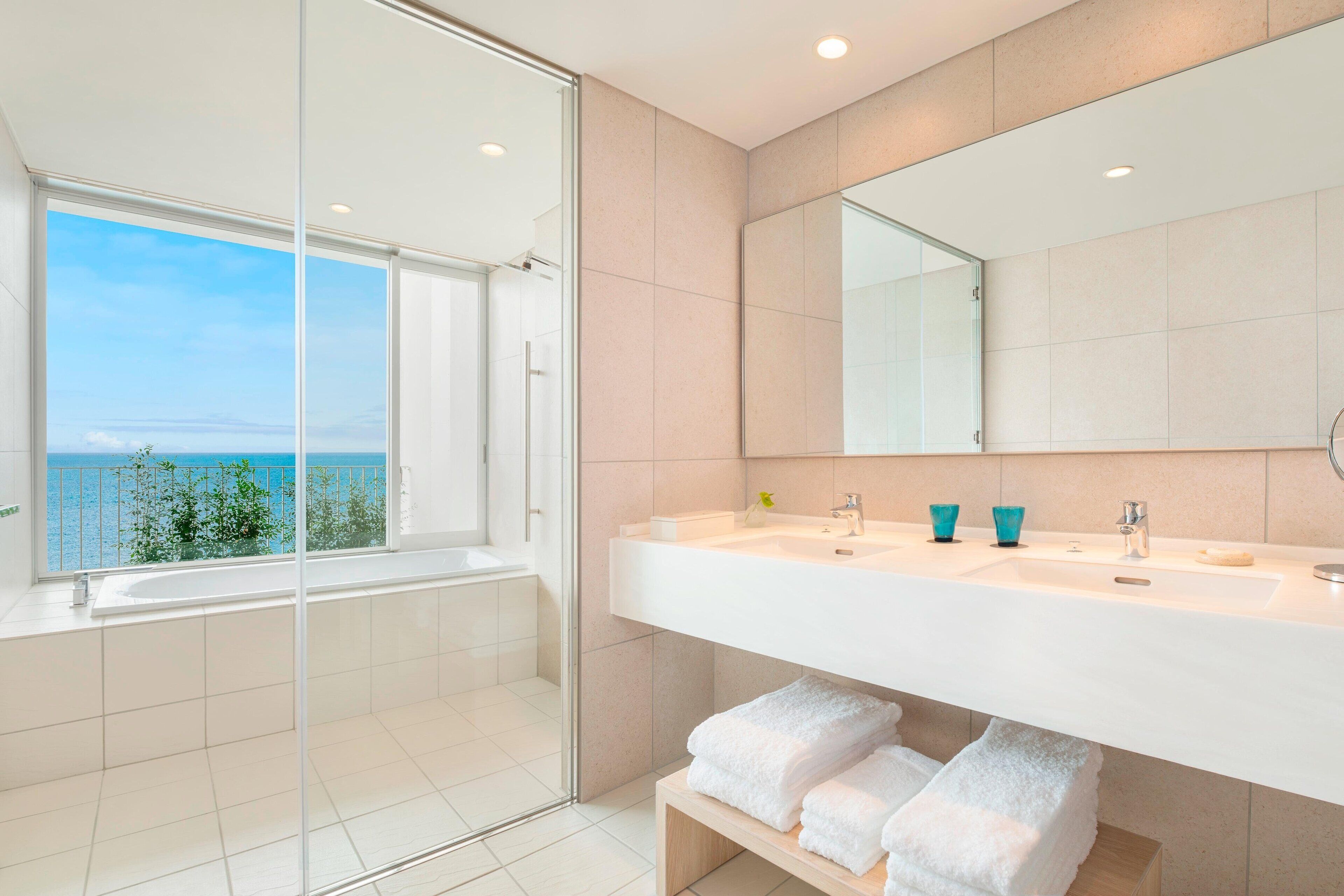 Ein modernes Badezimmer mit einem großen Fenster, einer Badewanne und einem Waschtisch mit zwei Becken.