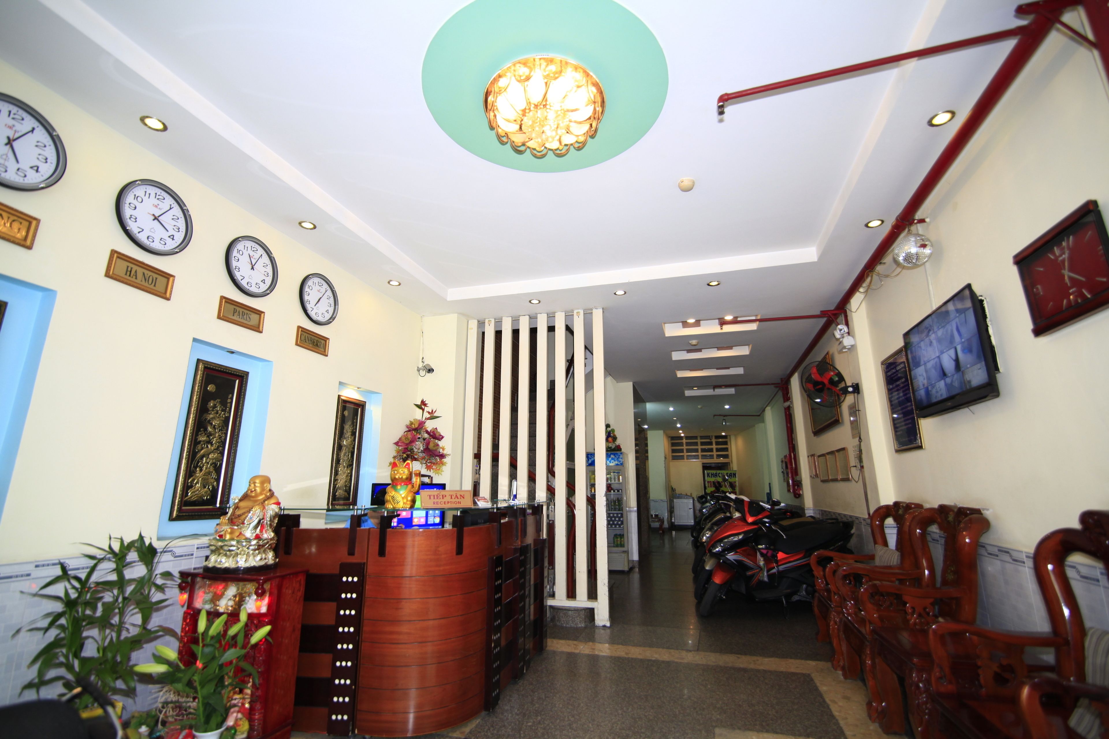 A reception area with a wooden reception desk, multiple clocks on the wall, and a ceiling light fixture.
