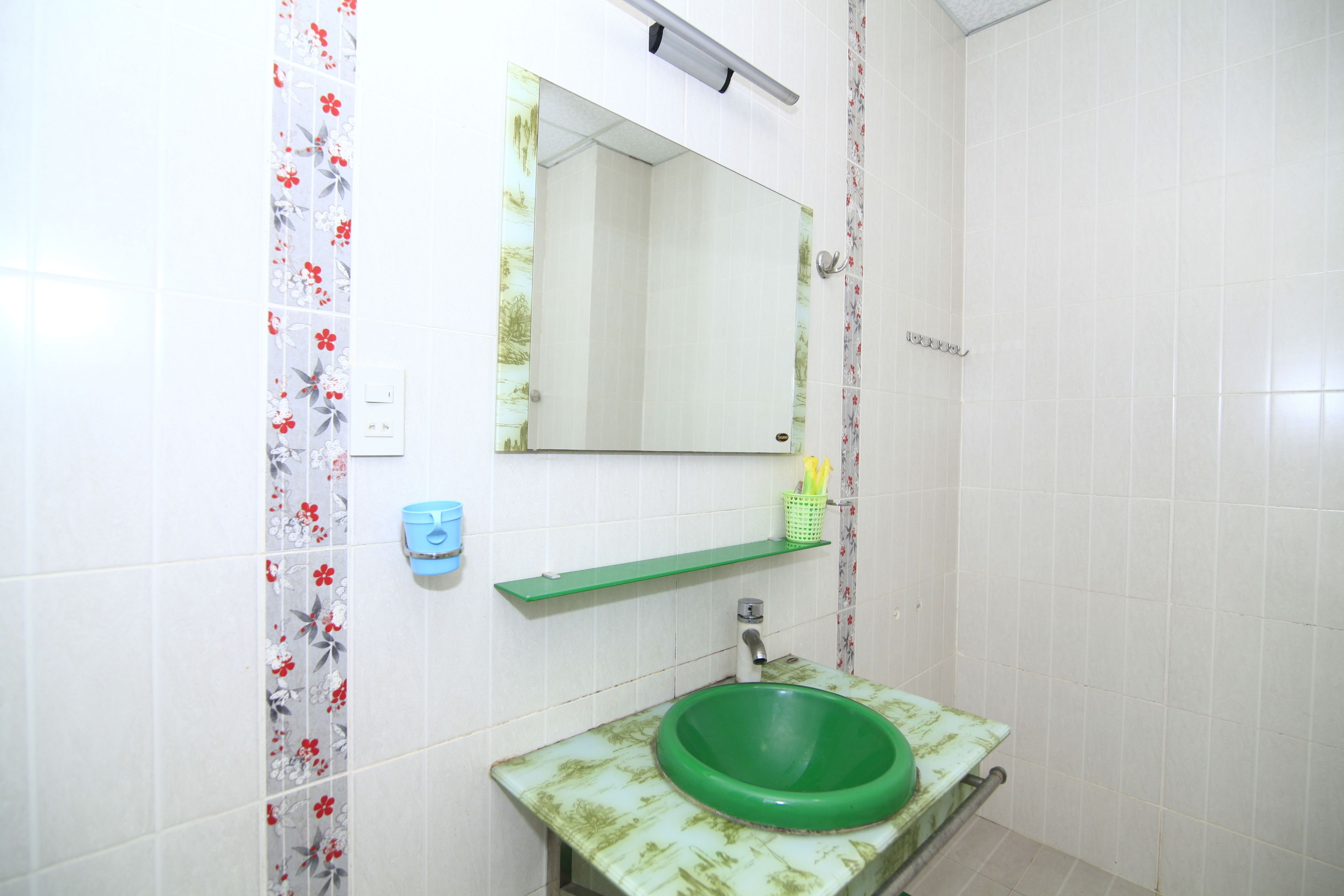 A bathroom with a green sink, a mirror, and a shower.