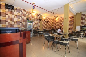 Un restaurant doté d’un comptoir d’accueil, de tables et de chaises.