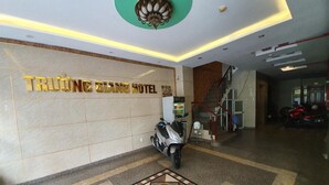 Zona de recepción de un hotel con pared de mármol, una patineta y una escalera.