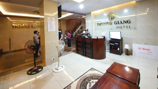 Zona de recepción de hotel con un mostrador, un ventilador y un cartel del Hotel Truong Giang.