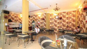 Un restaurante con paredes a cuadros, sillas de mimbre blancas y negras y mesas.