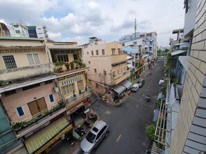 Une vue de rue avec des immeubles, une voiture garée et un magasin visible, reconnaissable à son enseigne.