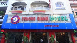 Un hotel con fachada azul y roja, balcones y un letrero de cafetería.