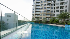 Een zwembad met helderblauwe tegels, omringd door een glazen balustrade en een gebouw met meerdere balkons op de achtergrond.