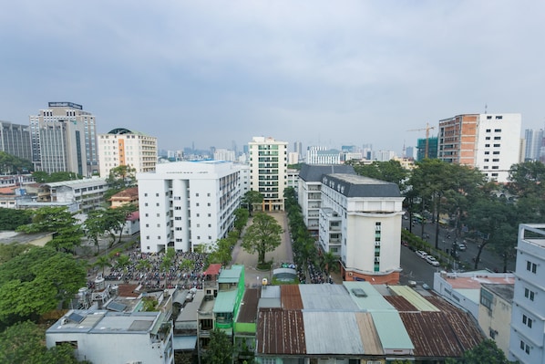 A cityscape with high-rise buildings, a central plaza with trees, and a crowd of people.