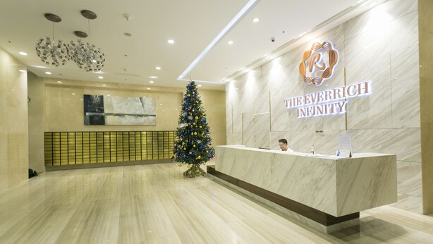 Een hotel receptie met een marmeren balie, een kerstboom en een bordje aan de muur met de tekst 'THE EVERRICH INFINITY'.