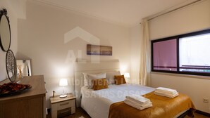 A hotel room with a bed, bedside tables, a nightstand, a window, and a view of the outside. - Ericeira Beach by ACasaDasCasas (Ericeira)