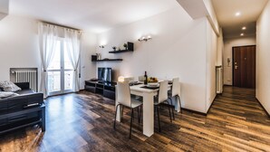 A modern living room with a sofa, a dining table with chairs, a TV, and a kitchen area with a fridge and a microwave. - Venice Ca 'Sole, big new apartment  (Venezia)
