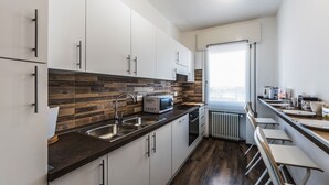 A modern kitchen with white cabinets, a dark countertop, and a wood backsplash. There is a window with a view, a sink, and a microwave. - Venice Ca 'Sole, big new apartment  (Venezia)