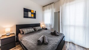 A modern bedroom with a large bed, a bedside table with a lamp, a wall art piece, and a window with curtains. - Venice Ca 'Sole, big new apartment  (Venezia)