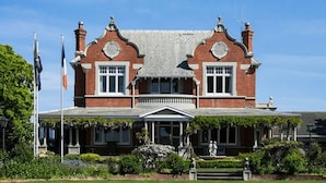 Un grand bâtiment à deux étages, construit en briques, doté d’une façade symétrique, de grandes fenêtres et d’une entrée centrale avec un porche.