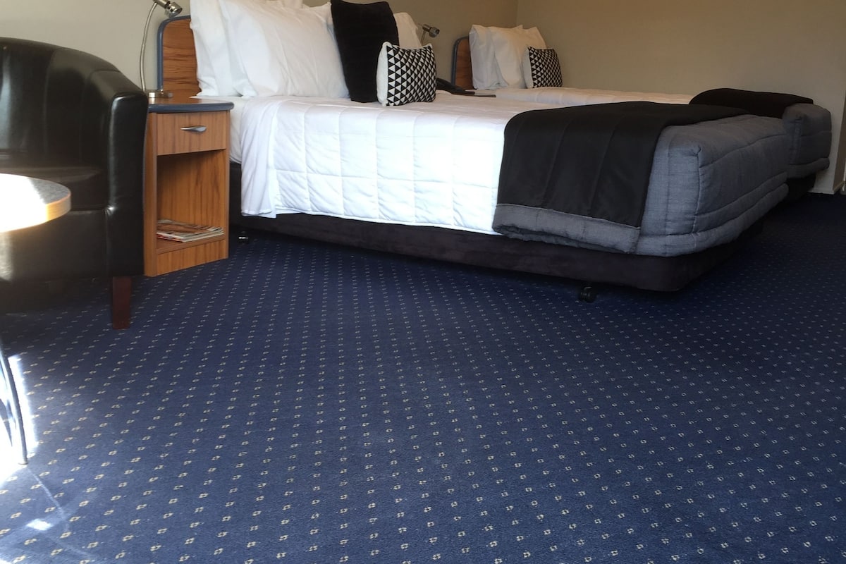A hotel room with a bed, a desk, and a chair.