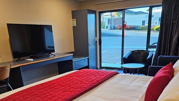 Une chambre d’hôtel avec un lit, une télévision, un bureau et une vue sur la rue.