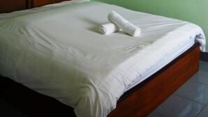 A single bed with a wooden headboard in a room with green walls and a ceiling fan. - All Day Hotel (Nong Khai)