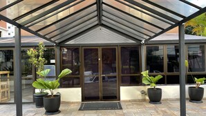 A covered entrance with large glass doors, potted plants, and a tiled floor.