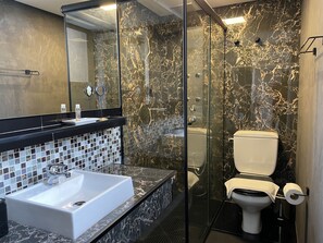 Une salle de bain moderne avec une douche à parois de verre, un lavabo blanc et des toilettes.