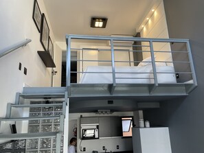 Una habitación de hotel compacta con literas, kitchenette y baño pequeño.