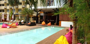A pool area with lounge chairs, a bar, and a restaurant. - Walking Street Hostel by New Wave - Adults Only (Koh Lipe)