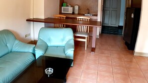 Un espacio habitable compacto con sofá, mesa de centro, kitchenette con microondas y refrigerador.