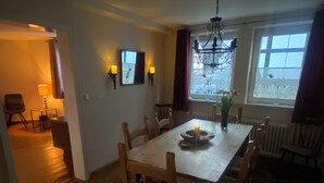 Ein Essbereich mit Tisch, Stühlen, einer Chandelier und Blick durch das Fenster.