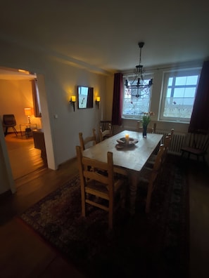 A dining area with a table, chairs, a chandelier, and a view through the window. - 5 bedrooms, quiet town location, garden, 2 parking spaces, 200m to market square (Goslar)