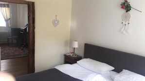 Ein Hotelzimmer mit Bett, Nachttisch mit Lampe, Wanddekoration in Herzform und Traumfänger.