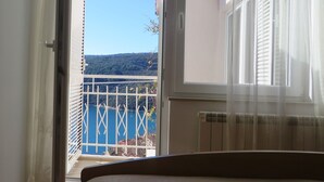Ein Schlafzimmer mit einem Bett, einem Fenster mit Blick auf einen Balkon und einer Tür, die nach draußen führt.