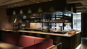 A modern bar area with a brick wall, stainless steel appliances, and a red cushioned seating area. - the square hotel GINZA (Tokyo)