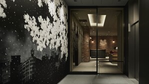 A hotel lobby with a modern design, featuring a glass door entrance, a brick wall, and a cityscape mural on the left. - the square hotel GINZA (Tokyo)