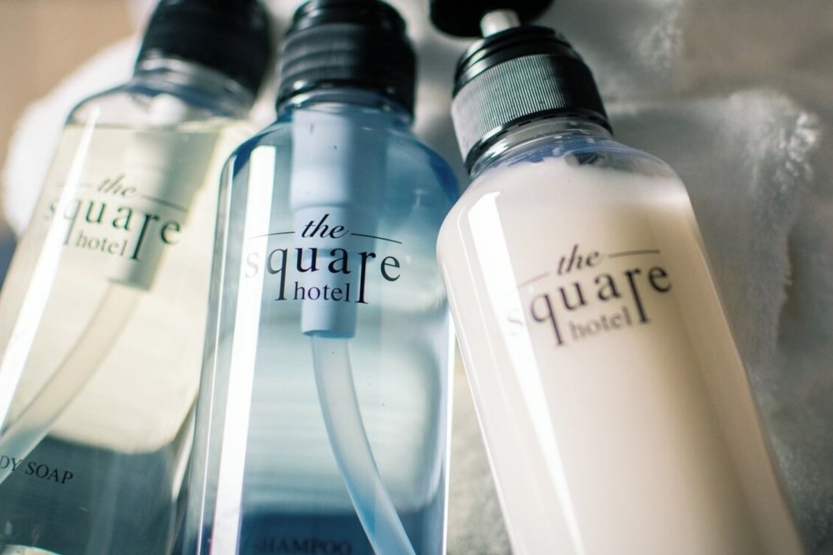 Three bottles of body soap with the label 'the square hotel' on them.