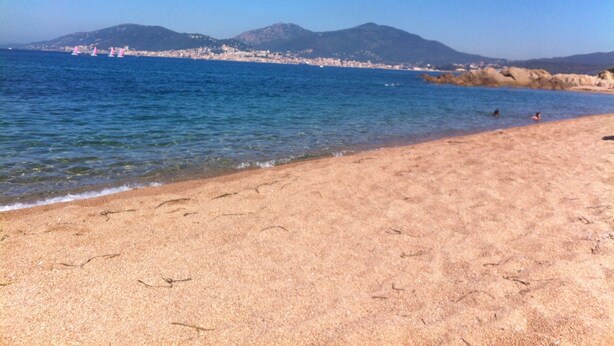 A beach with clear water, a sandy shore, and distant mountains. - rent large calm F1 at the door of the center town of Ajaccio (Sarrola-Carcopino)