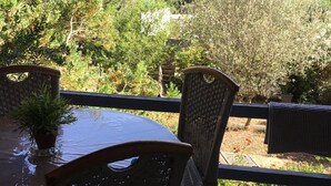 A patio with a round table and wicker chairs, overlooking a hilly landscape with greenery and buildings. - rent large calm F1 at the door of the center town of Ajaccio (Sarrola-Carcopino)