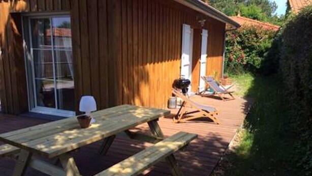 Una terraza de madera con una mesa de picnic y sillas de descanso.