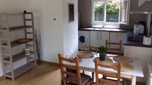 Cocina compacta con lavadora, pileta y ventana con vista a follaje.