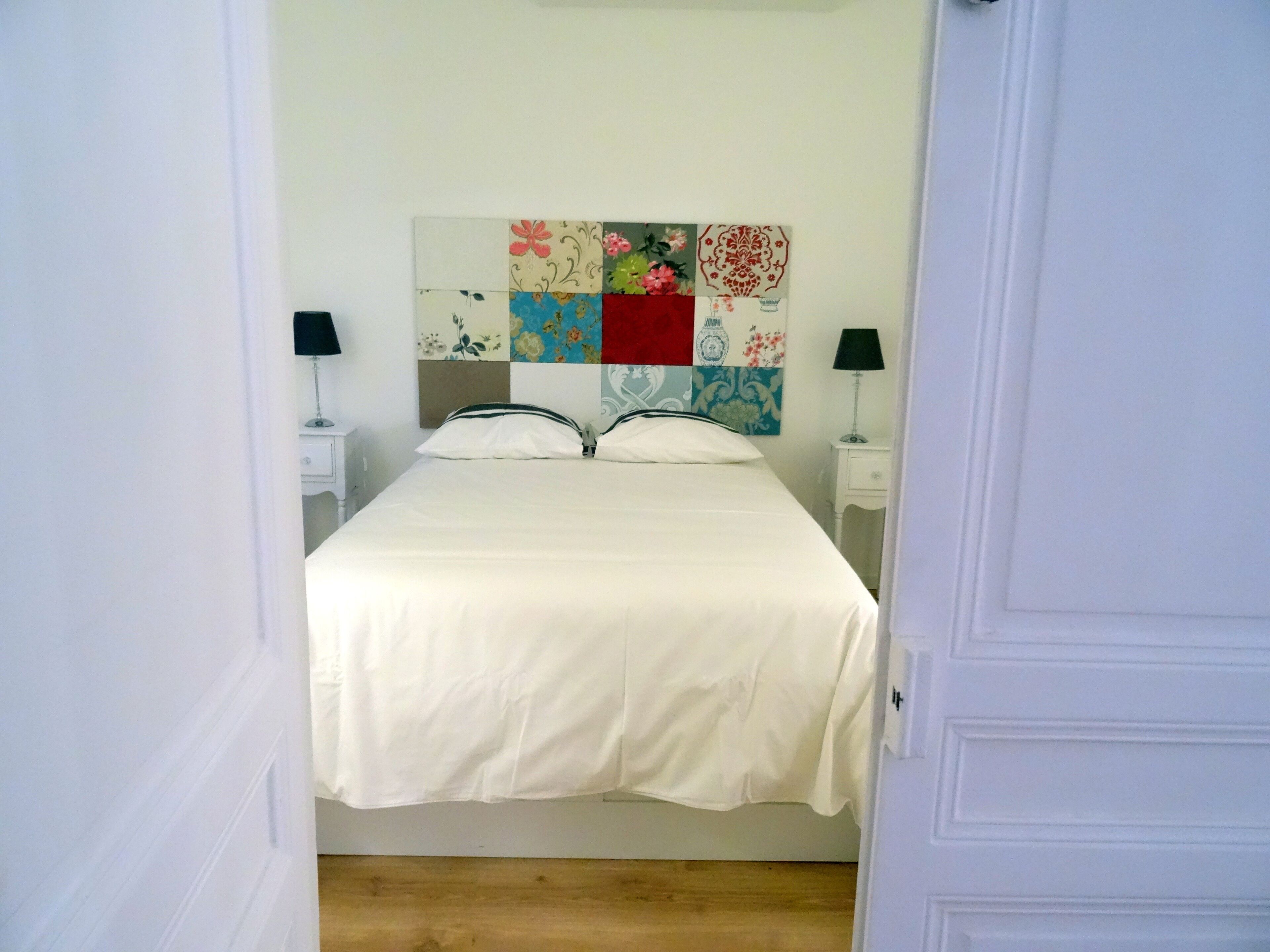 A bedroom with a bed, two bedside tables, and a colorful headboard.