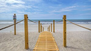 Ein hölzerner Steg führt zum Strand, mit einem Schild, das davor warnt, die Dünen nicht zu betreten.
