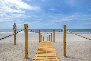 Ein hölzerner Steg führt zum Strand, mit einem Schild, das davor warnt, die Dünen nicht zu betreten.