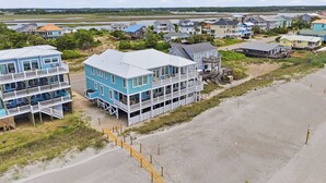Eine Küstenwohngegend mit Strandhäusern, die mehrere Stockwerke, Balkone und Holzstege zum Strand bieten.