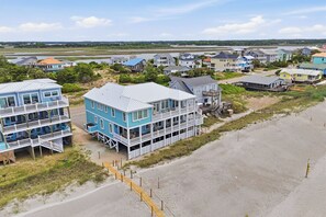 Eine Küstenwohngegend mit Strandhäusern, die mehrere Stockwerke, Balkone und Holzstege zum Strand bieten.