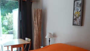 A room with a bed, a table, a chair, a lamp, and a window with curtains. - STUDIO IN A SEA FACING RESIDENCE WITH GARDEN VIEW (Boulogne-sur-Mer)