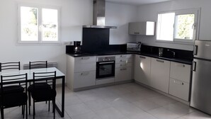 A modern kitchen with white cabinets, a black countertop, and a dining table with chairs.