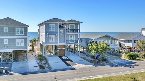 A beachfront residential area with houses elevated on stilts, featuring balconies and direct ocean views. - Don't Worry Beach Happy: Ocean View, Swimming Pool (Oak Island)