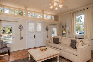 Relax in this spacious living room with a high ceiling, sofa, coffee table, and window with a view.