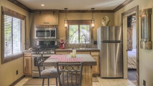 Una cocina con una isla central, electrodomésticos de acero inoxidable y una ventana con persianas.