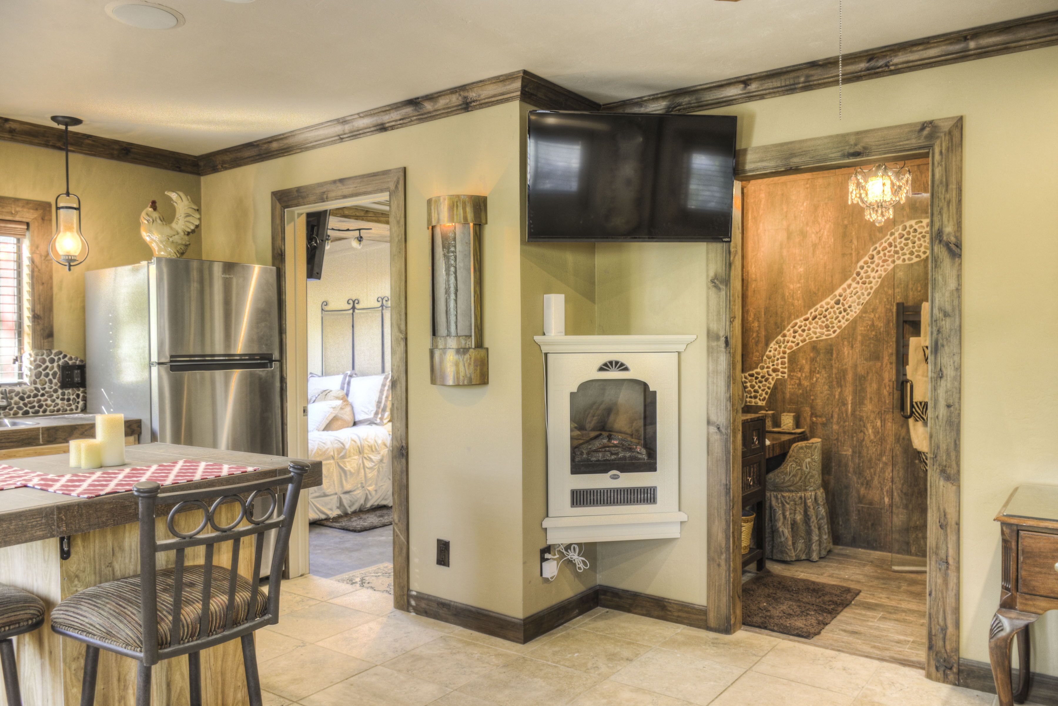 Una cocina con refrigerador de acero inoxidable, horno empotrado, chimenea y comedor con mesa y sillas.