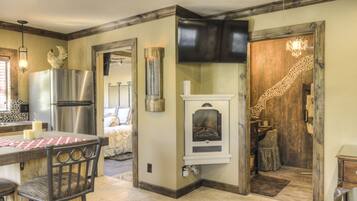 Una cocina con refrigerador de acero inoxidable, horno empotrado, chimenea y comedor con mesa y sillas.