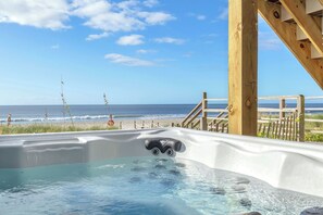 A hot tub with a wooden deck and a view of the beach. - The Beachcomber: Spacious, Family-friendly, Dog-friendly, Oceanfront Home with G (Oak Island)